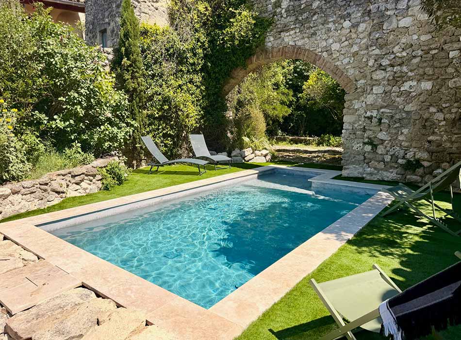 Un espace piscine central dans le jardin, bordé par une arche